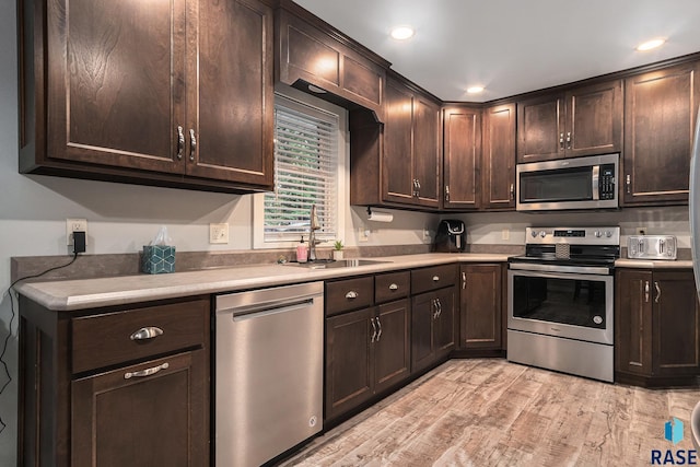 1034 N Elmwood Ave, Luverne, MN 56156 - kitchen featuring appliances with stainless steel finishes, a sink, dark brown cabinetry, light wood-style floors, and light countertops