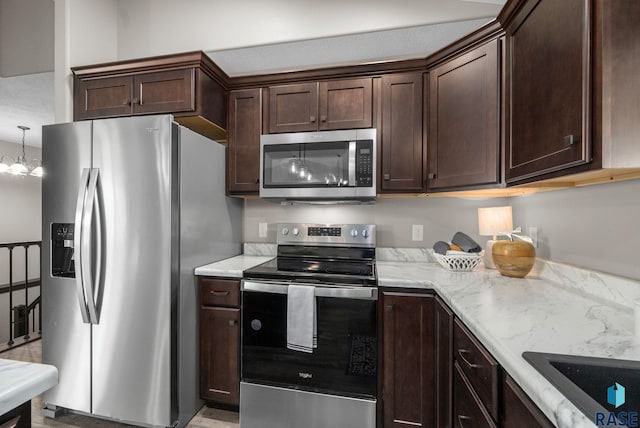 525 Quartzite Ave, Tea, SD 57064 - kitchen with appliances with stainless steel finishes, dark brown cabinets, light stone countertops, and a chandelier