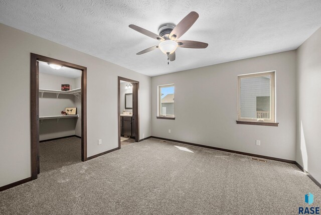 525 Quartzite Ave, Tea, SD 57064 - unfurnished bedroom featuring a walk in closet, carpet flooring, baseboards, a textured ceiling, and a closet