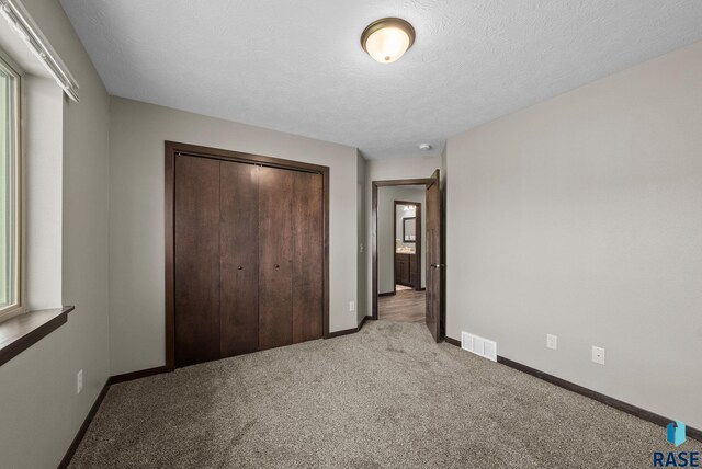 525 Quartzite Ave, Tea, SD 57064 - unfurnished bedroom featuring light carpet, a closet, baseboards, and a textured ceiling