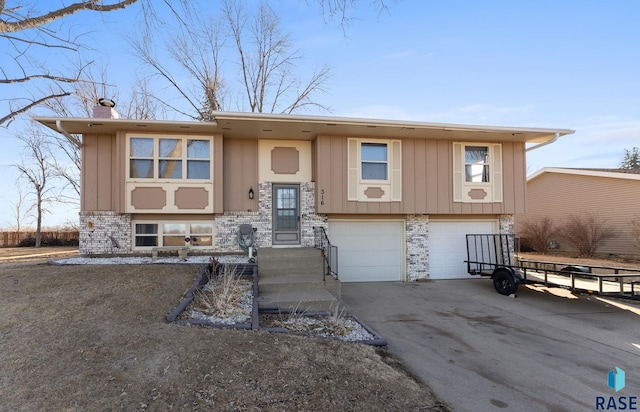 316 S Norbeck St, Vermillion, SD 57069 - split foyer home featuring board and batten siding, a garage, brick siding, and concrete driveway
