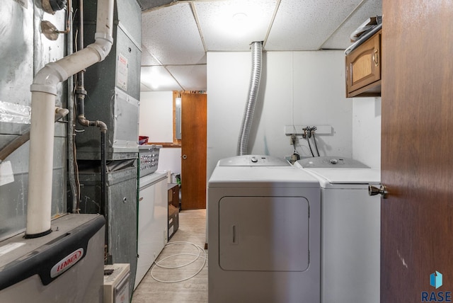 316 S Norbeck St, Vermillion, SD 57069 - washroom with washer and clothes dryer, heating unit, cabinet space, and light wood finished floors
