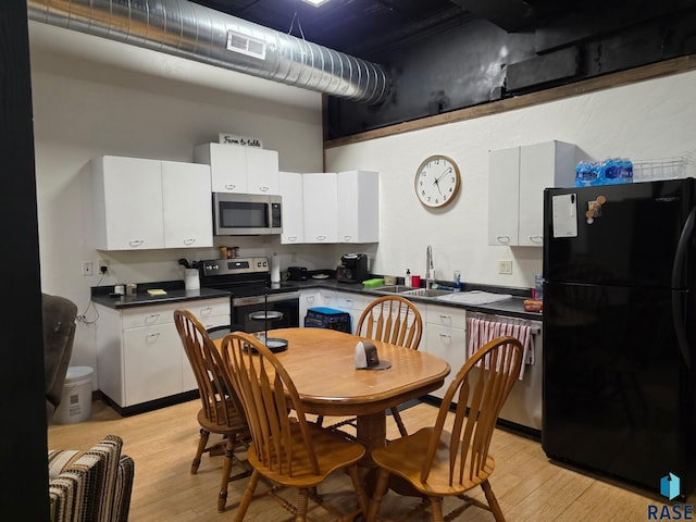 231 S 5th St, Menno, SD 57045 - kitchen featuring appliances with stainless steel finishes, a sink, dark countertops, light wood-style floors, and white cabinets