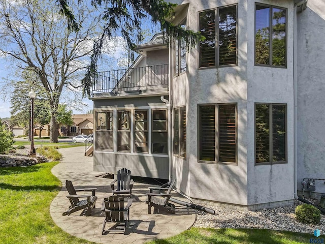 2502 S Big Timber Pl, Sioux Falls, SD 57105 - back of property featuring a balcony, stucco siding, a patio area, a yard, and a sunroom