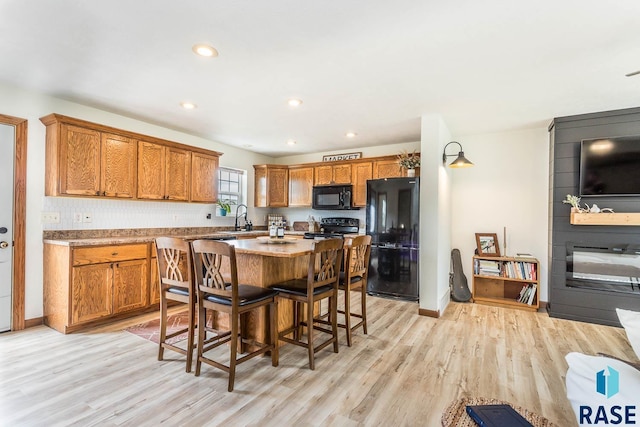 1808 S Mulberry Ave Unit D, Brandon, SD 57005 - kitchen featuring black appliances, light wood-style floors, brown cabinets, a breakfast bar area, and recessed lighting