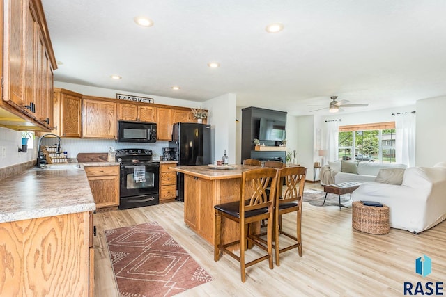 1808 S Mulberry Ave Unit D, Brandon, SD 57005 - kitchen featuring black appliances, a sink, light wood finished floors, a breakfast bar, and a center island