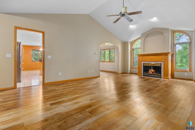 6700 W Snowberry Cir, Sioux Falls, SD 57106 - unfurnished living room featuring ceiling fan, a glass covered fireplace, light wood finished floors, arched walkways, and baseboards