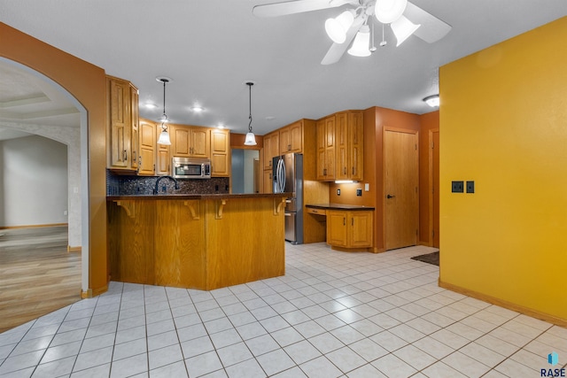 6700 W Snowberry Cir, Sioux Falls, SD 57106 - kitchen with stainless steel appliances, a peninsula, dark countertops, arched walkways, and a ceiling fan