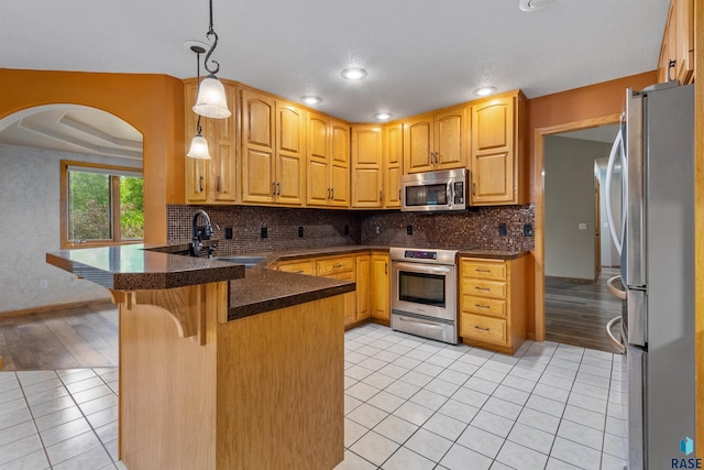 6700 W Snowberry Cir, Sioux Falls, SD 57106 - kitchen featuring appliances with stainless steel finishes, a sink, a peninsula, light tile patterned floors, and backsplash