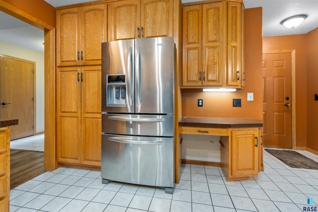 6700 W Snowberry Cir, Sioux Falls, SD 57106 - kitchen featuring stainless steel refrigerator with ice dispenser, light tile patterned floors, brown cabinetry, and dark countertops