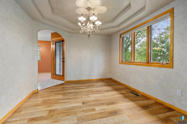 6700 W Snowberry Cir, Sioux Falls, SD 57106 - unfurnished room with wood finished floors, a tray ceiling, arched walkways, a chandelier, and baseboards