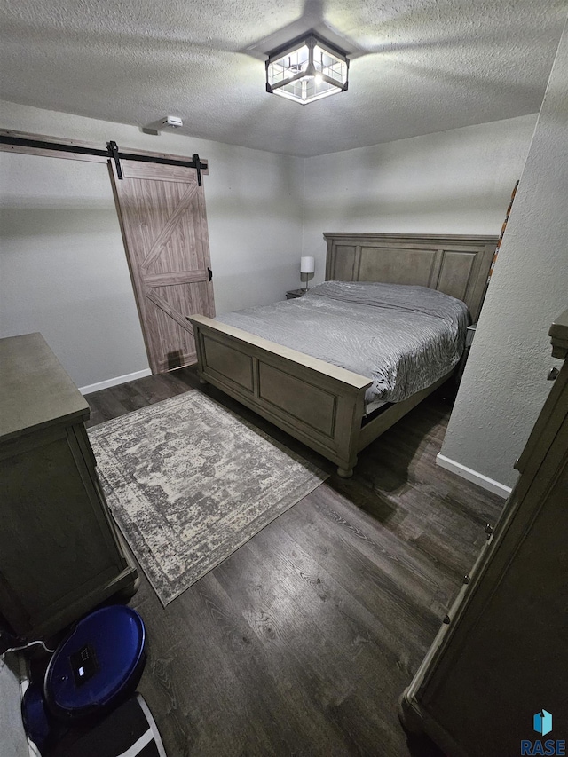 511 N 3rd St, Emery, SD 57332 - bedroom with dark wood-type flooring, a barn door, and a textured ceiling