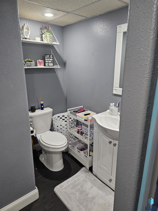 511 N 3rd St, Emery, SD 57332 - half bathroom featuring toilet, vanity, a textured wall, baseboards, and wood finished floors