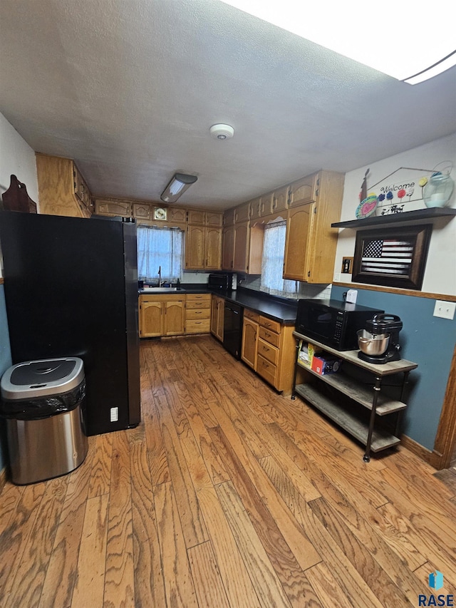 511 N 3rd St, Emery, SD 57332 - kitchen with black appliances, a sink, hardwood / wood-style floors, dark countertops, and brown cabinetry