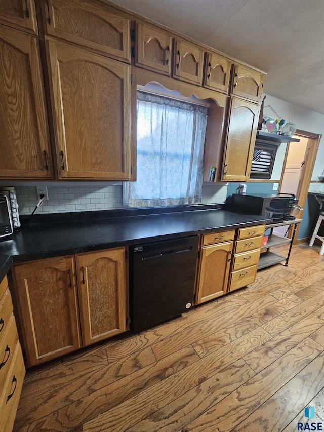 511 N 3rd St, Emery, SD 57332 - kitchen featuring black dishwasher, dark countertops, tasteful backsplash, wood finished floors, and brown cabinetry