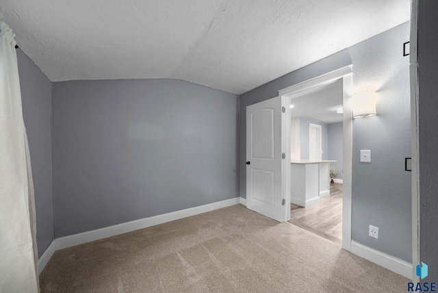 209 E Elm St, Harrisburg, SD 57032 - additional living space featuring vaulted ceiling, light carpet, baseboards, and a textured ceiling