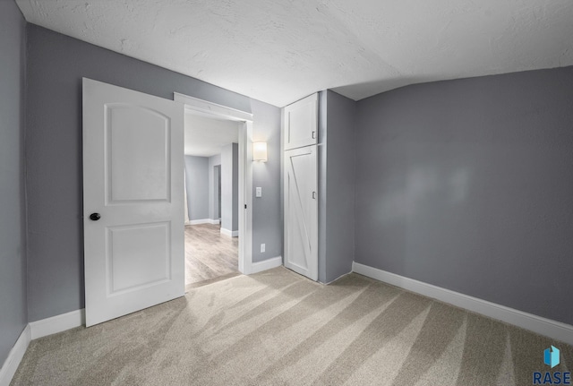 209 E Elm St, Harrisburg, SD 57032 - unfurnished bedroom with light colored carpet, baseboards, a textured ceiling, vaulted ceiling, and a closet