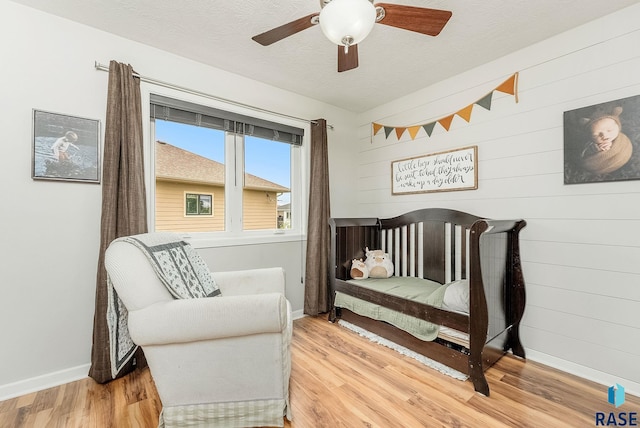 1302 Ripple Creek Rd, Dell Rapids, SD 57022 - bedroom featuring wood walls, baseboards, wood finished floors, a textured ceiling, and a ceiling fan