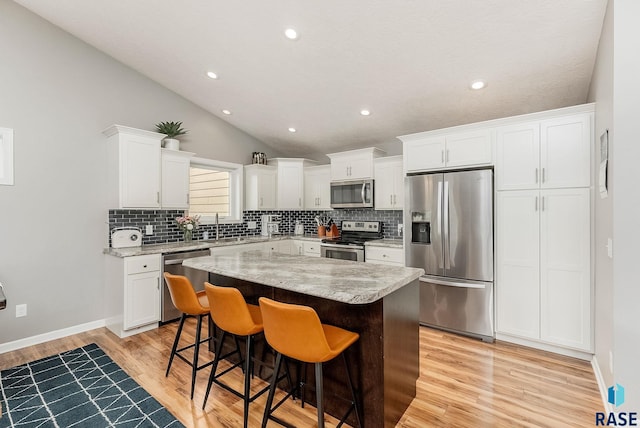 1302 Ripple Creek Rd, Dell Rapids, SD 57022 - kitchen with stainless steel appliances, tasteful backsplash, a kitchen island, light wood-type flooring, and vaulted ceiling