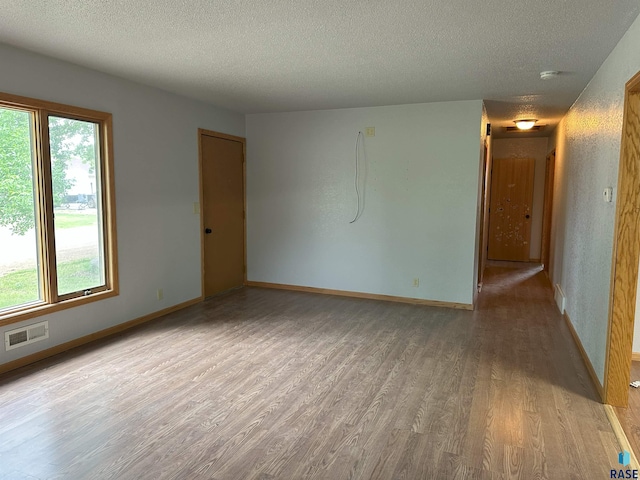 800 N Poplar St, Bridgewater, SD 57319 - unfurnished room with wood finished floors, a textured ceiling, healthy amount of natural light, baseboards, and a smoke detector