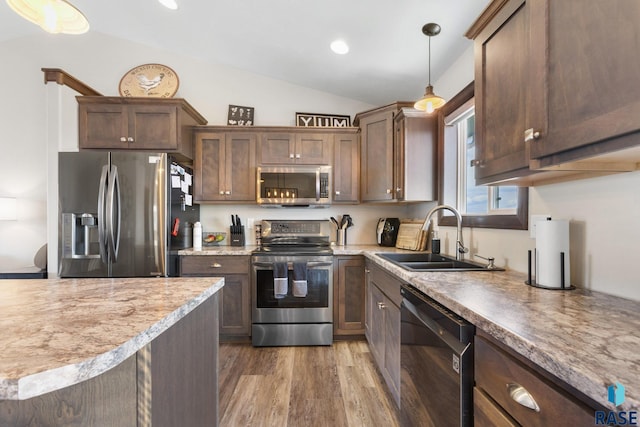 7305 W Jacob Cir, Sioux Falls, SD 57106 - kitchen featuring stainless steel appliances, a sink, vaulted ceiling, wood finished floors, and hanging light fixtures