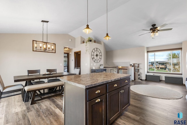 7305 W Jacob Cir, Sioux Falls, SD 57106 - kitchen with vaulted ceiling, a kitchen island, dark wood-style flooring, decorative light fixtures, and open floor plan