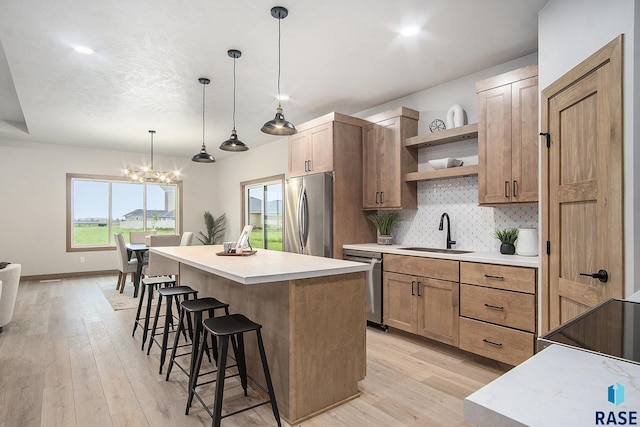 501 S Huckleberry Trl, Harrisburg, SD 57032 - kitchen featuring appliances with stainless steel finishes, a sink, open shelves, a breakfast bar, and a center island