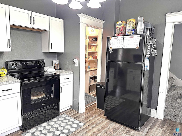 816 W 4th St, Canton, SD 57013 - kitchen with black appliances, light wood finished floors, white cabinetry, and light stone countertops