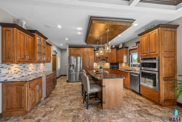 1301 S Hyannis Port Ln, Sioux Falls, SD 57106 - kitchen featuring appliances with stainless steel finishes, brown cabinets, a kitchen island, dark stone counters, and glass insert cabinets