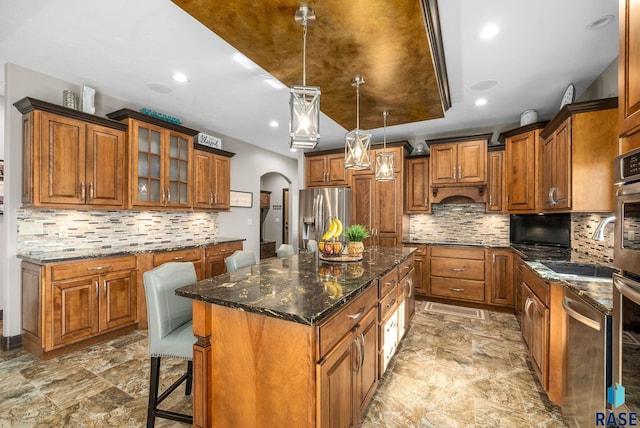 1301 S Hyannis Port Ln, Sioux Falls, SD 57106 - kitchen featuring appliances with stainless steel finishes, a center island, brown cabinetry, arched walkways, and recessed lighting