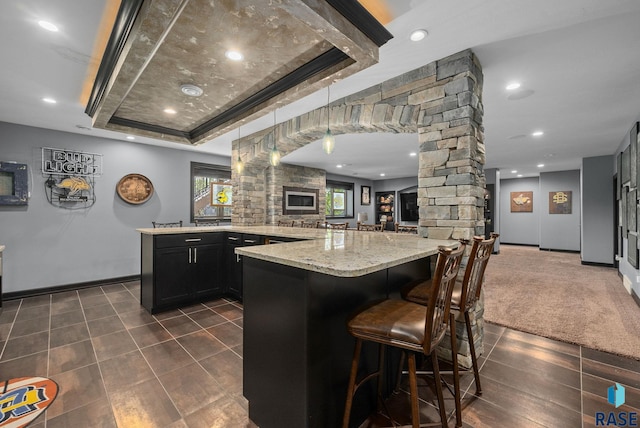 1301 S Hyannis Port Ln, Sioux Falls, SD 57106 - kitchen featuring baseboards, decorative columns, a raised ceiling, light stone counters, and open floor plan