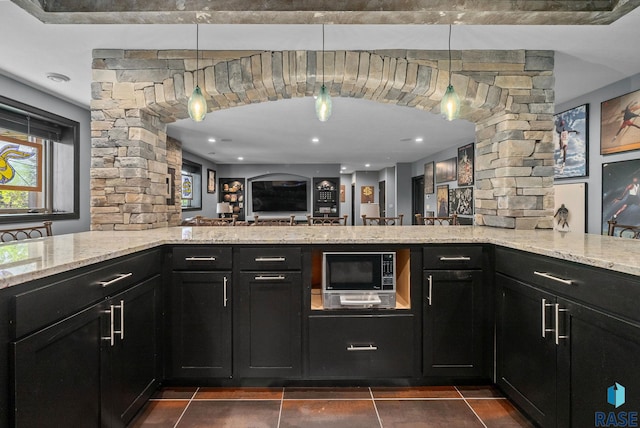 1301 S Hyannis Port Ln, Sioux Falls, SD 57106 - kitchen with ornate columns, built in microwave, dark cabinets, light stone countertops, and dark tile patterned floors