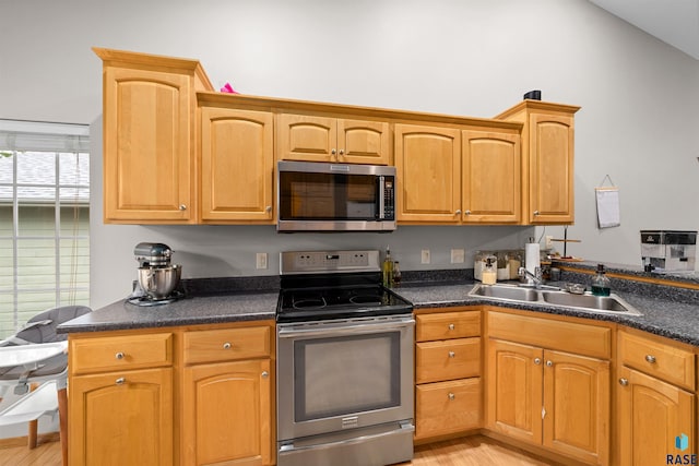 7308 W 53rd St, Sioux Falls, SD 57106 - kitchen with appliances with stainless steel finishes, a sink, light wood-style flooring, dark countertops, and lofted ceiling