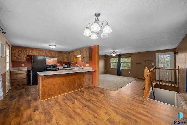 1300 S Point Dr, Sioux Falls, SD 57103 - kitchen with black appliances, dark wood finished floors, brown cabinetry, a peninsula, and light countertops