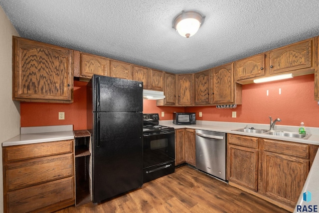 1300 S Point Dr, Sioux Falls, SD 57103 - kitchen with black appliances, a sink, under cabinet range hood, a textured ceiling, and dark wood finished floors
