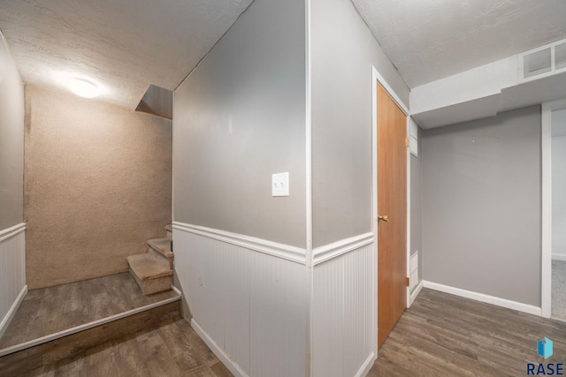 1300 S Point Dr, Sioux Falls, SD 57103 - below grade area with wood finished floors, stairs, a textured ceiling, baseboards, and wainscoting