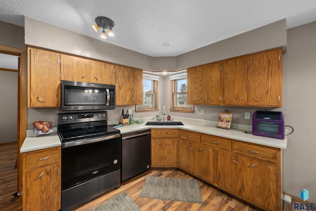 350 W Maple St, Edgerton, MN 56128 - kitchen featuring stainless steel appliances, a sink, light wood-type flooring, a textured ceiling, and light countertops