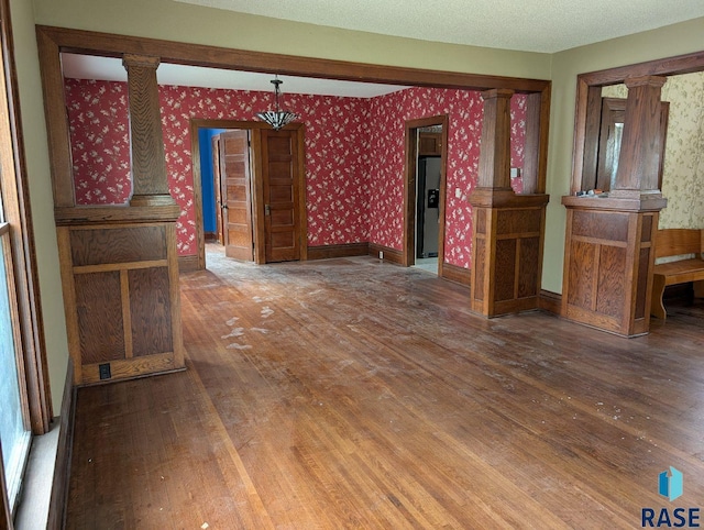 302 E 19th St, Sioux Falls, SD 57105 - unfurnished living room with ornate columns, wood finished floors, and wallpapered walls