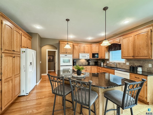 108 W Hazeltine Ln, Sioux Falls, SD 57108 - kitchen featuring white appliances, arched walkways, a sink, light wood-type flooring, and tasteful backsplash