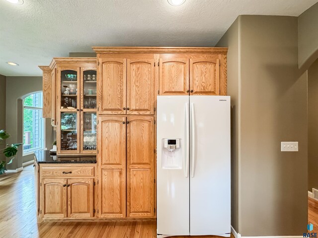 108 W Hazeltine Ln, Sioux Falls, SD 57108 - kitchen featuring white fridge with ice dispenser, arched walkways, light wood-type flooring, glass insert cabinets, and baseboards