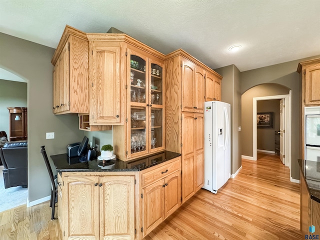 108 W Hazeltine Ln, Sioux Falls, SD 57108 - kitchen featuring white fridge with ice dispenser, arched walkways, glass insert cabinets, light wood-type flooring, and baseboards