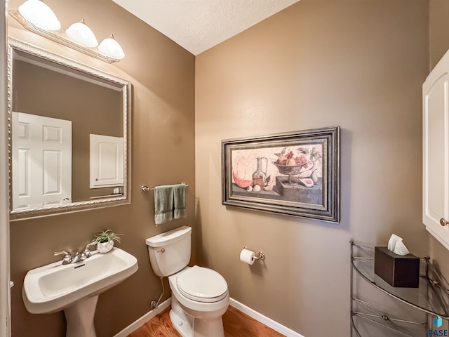 108 W Hazeltine Ln, Sioux Falls, SD 57108 - half bath with toilet, baseboards, a sink, wood finished floors, and a textured ceiling