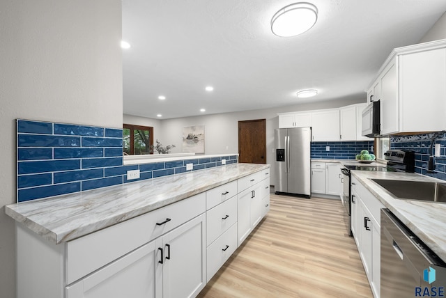 1912 E Sylvan Cir, Brandon, SD 57005 - kitchen with appliances with stainless steel finishes, light wood-style flooring, white cabinets, tasteful backsplash, and light stone countertops