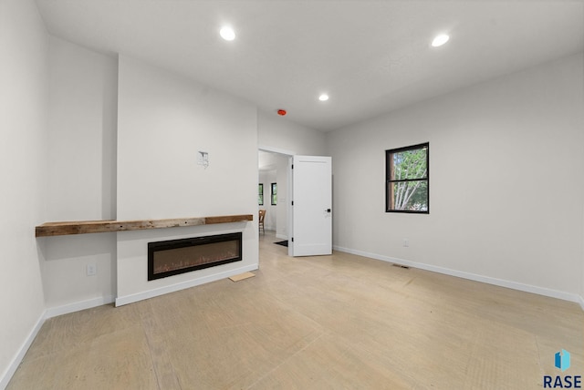 1709 S Duluth Ave, Sioux Falls, SD 57105 - unfurnished living room featuring recessed lighting, a glass covered fireplace, baseboards, and light wood-style floors