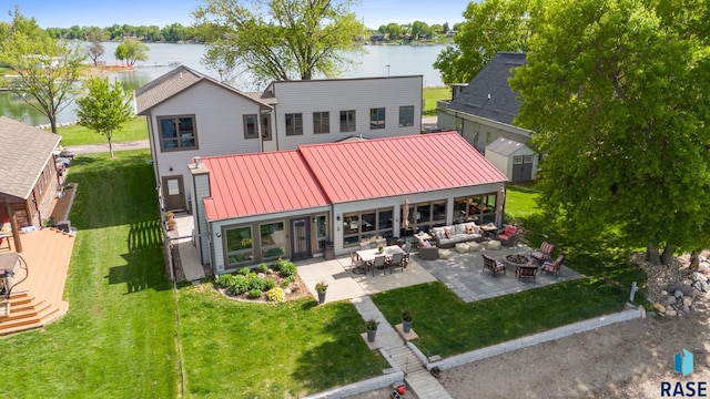 6604 Peninsula Pt, Wentworth, SD 57075 - back of house with a patio area, an outdoor living space with a fire pit, a water view, metal roof, and a lawn