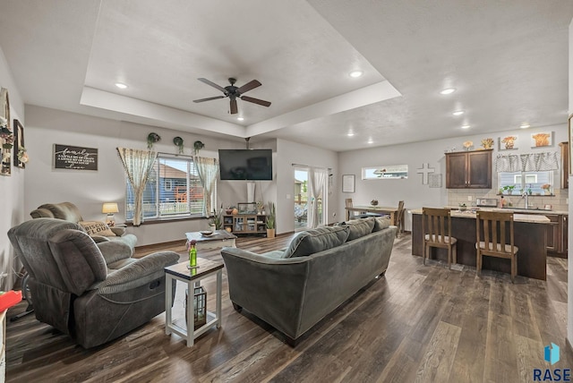 5205 S Eastwind Ave, Sioux Falls, SD 57108 - living room featuring a tray ceiling, dark wood-style floors, a ceiling fan, recessed lighting, and baseboards