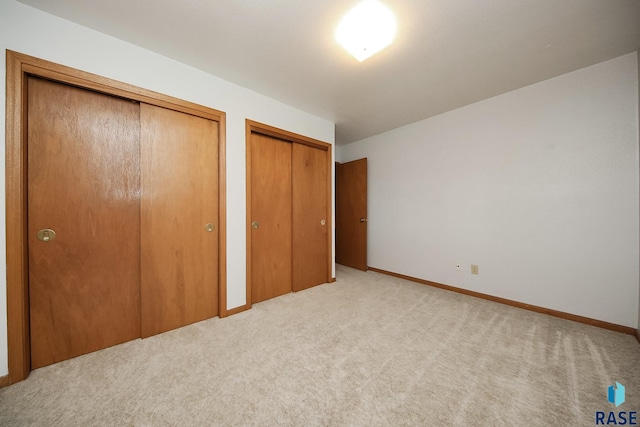 121 S Elm St, Lennox, SD 57039 - unfurnished bedroom with two closets, carpet flooring, and baseboards