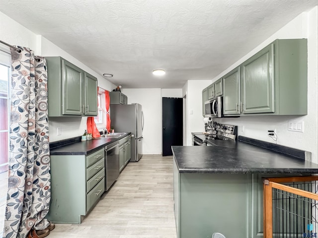 101 N Pipestone St Unit 3, Brandon, SD 57005 - kitchen with appliances with stainless steel finishes, green cabinets, light wood-style flooring, a peninsula, and a textured ceiling