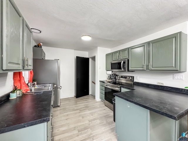 101 N Pipestone St Unit 3, Brandon, SD 57005 - kitchen with stainless steel appliances, light wood-style floors, dark countertops, a peninsula, and a textured ceiling