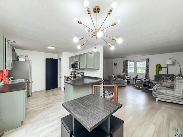 101 N Pipestone St Unit 3, Brandon, SD 57005 - kitchen with dark countertops, stainless steel appliances, a chandelier, open floor plan, and light wood finished floors